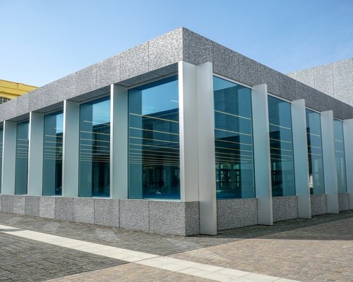 External architecture of an elegant metropolitan community library with clean stone lines and glass panels