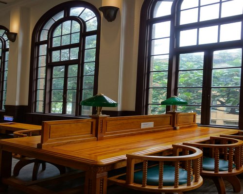 Bright reading room showing wooden desks equipped with outlets and books under cozy lighting